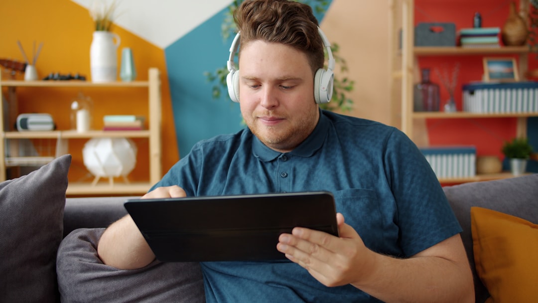 Man wearing headphones using a tablet on the couch.
